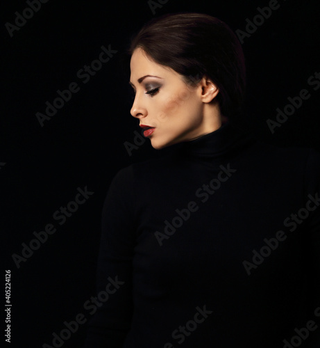 Sexy woman with bright evening makeup, red lipstick brown brow posing isolated on dark black background. Closeup portrait in deep low key light shadows. Art.