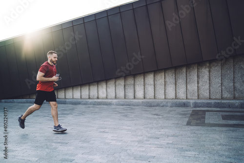 Sportsman running on street in earphones