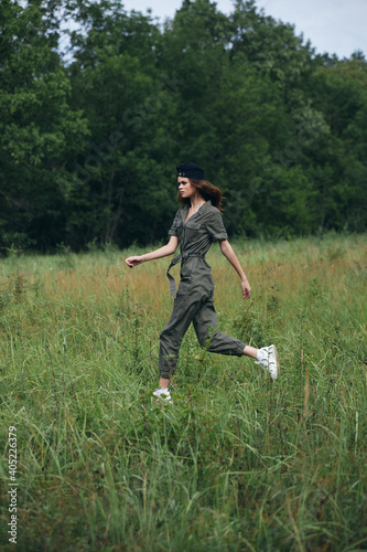 Woman in the field runs on the grass in a green jumpsuit  © SHOTPRIME STUDIO