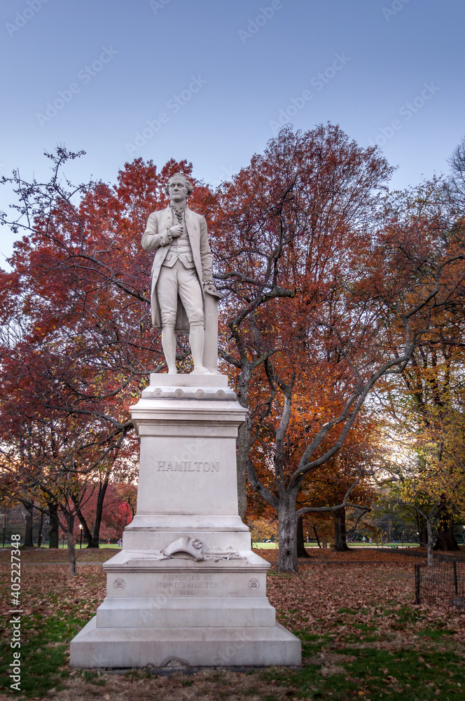 Central Park, Manhattan, New York, USA - November 18, 2016.
An outdoor standing granite sculpture of Alexander Hamilton by Carl Conrads is standing in a grove of apple trees and crabapples.