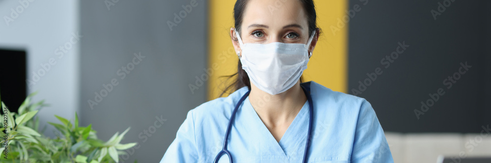 Doctor with protective medical mask siting at table in office and writing in documents. Medical education concept Doctor with protective medical mask siting at table in office and writing in documents. Medical education concept