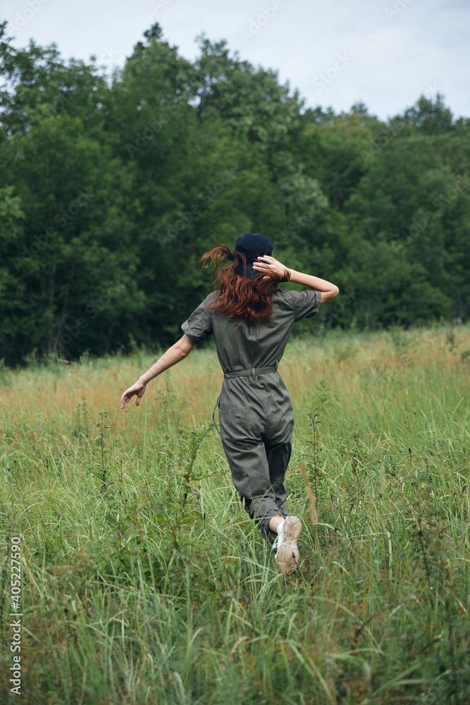 Womanruns across the field in green jumpsuit Freedom back view Womanruns across the field in green jumpsuit Freedom back view