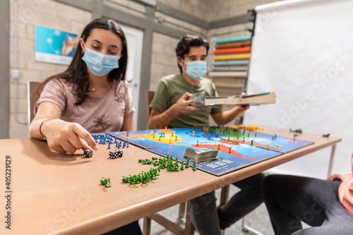 Group of youths with face masks playing a board game.