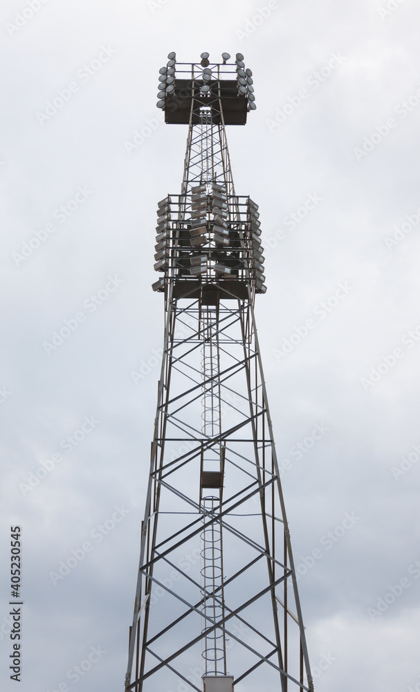 Giant lighting tower with a lot of lights against blue sky in vertical composition Giant lighting tower with a lot of lights against blue sky in vertical composition