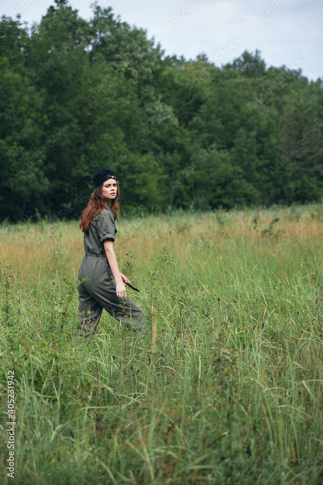 Woman in the meadow Walk in green jumpsuit black cap Woman in the meadow Walk in green jumpsuit black cap