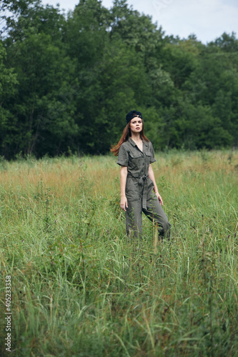 woman outdoors Green jumpsuit black cap tall grass 