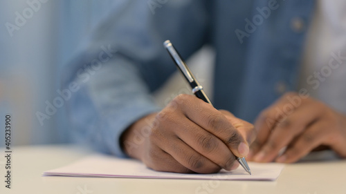 Hands of African Man Writing on Paper with Pen, Close Up