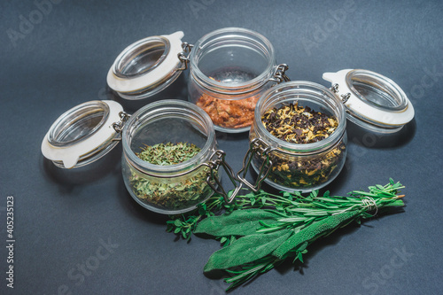 Different varieties traditional black, red and green tea in glass jar and on a metal spoon on gray background