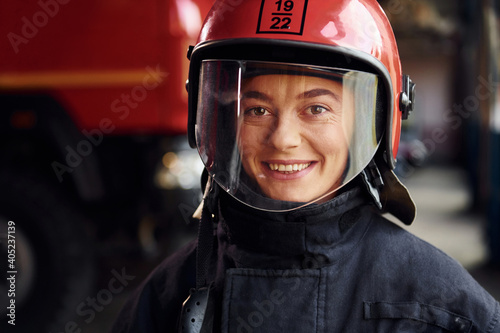 Close up view. Female firefighter in protective uniform standing near truck