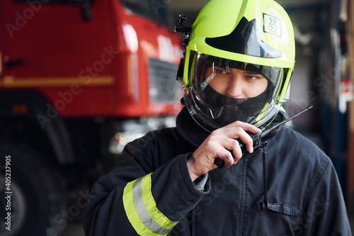 Male firefighter in protective uniform standing near truck photo