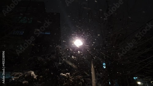 A lot of snow falling countlessly around bright street lights on a dark evening