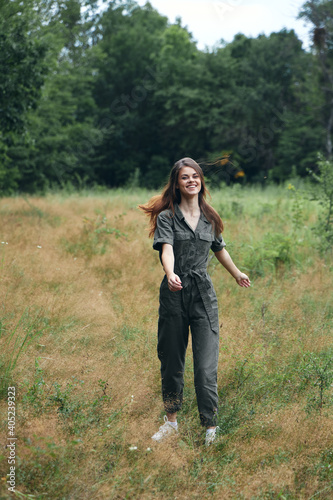 Cheerful woman in green jumpsuit walking in the woods resting  © SHOTPRIME STUDIO