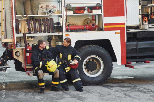 Male and female firefighters in protective uniform is outdoors together