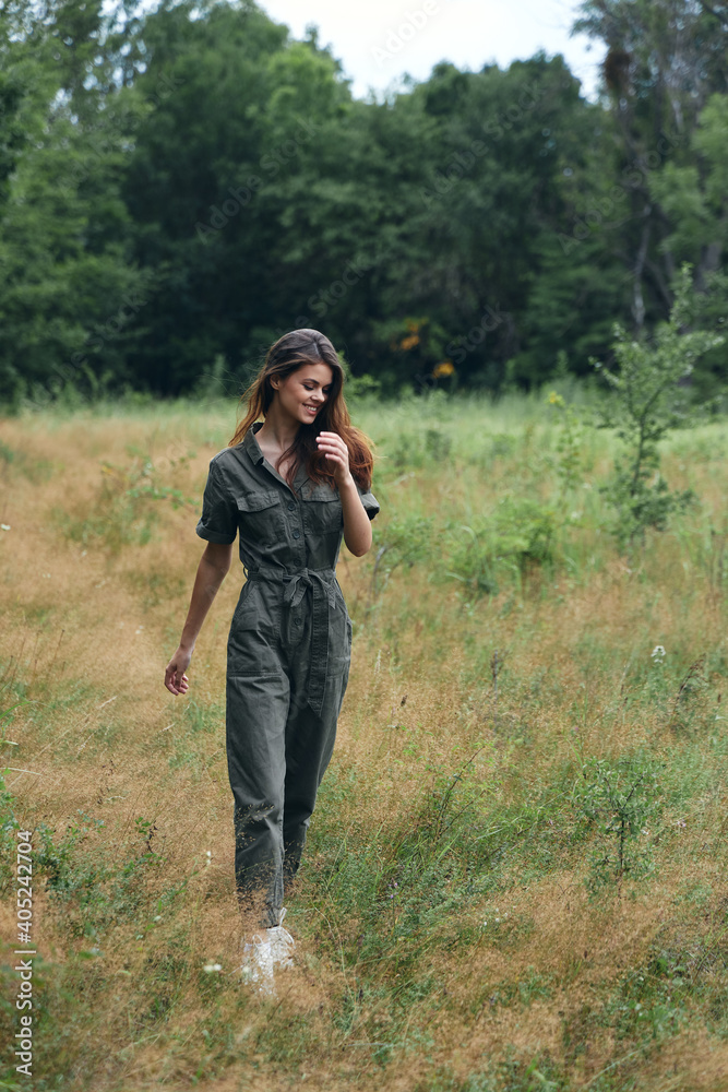 Woman in the forest walking through the field red hair green suit Woman in the forest walking through the field red hair green suit
