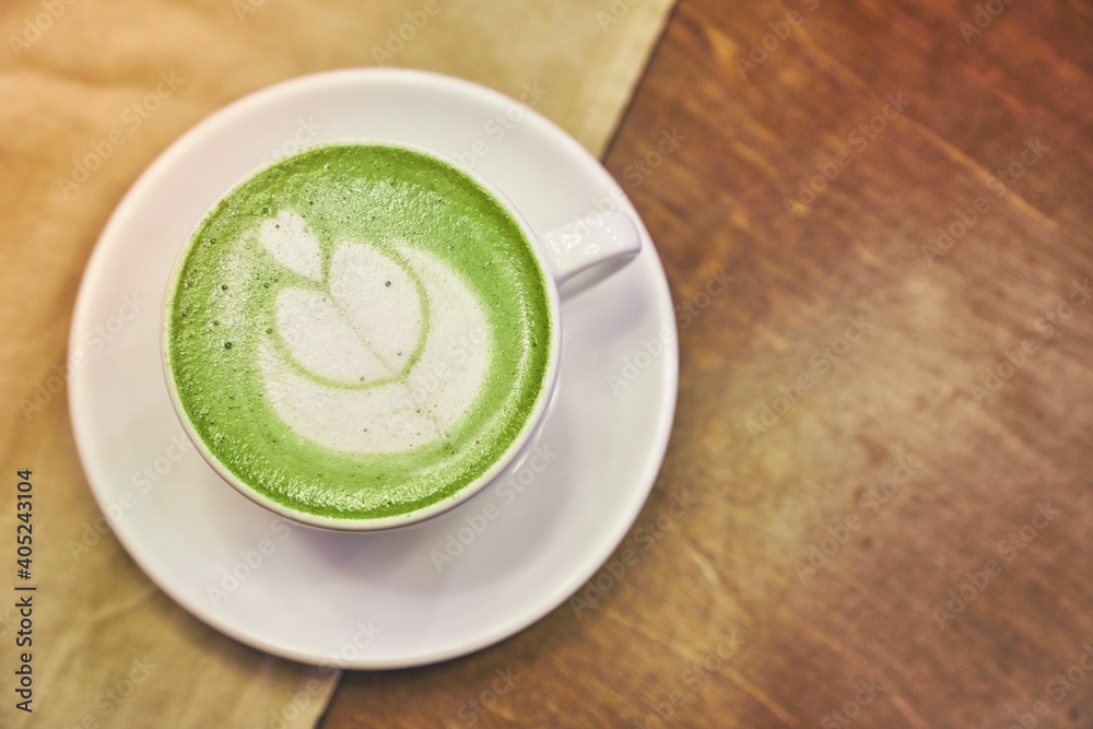 Cup of matcha latte on wooden background and a beige napkin in a cafe with copy space. High quality photo Cup of matcha latte on wooden background and a beige napkin in a cafe with copy space. High quality photo