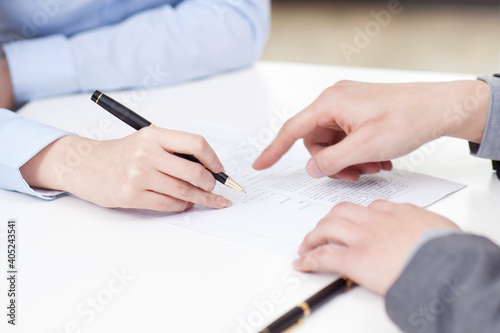 Businesswoman signing document businessman pointing at desk in office