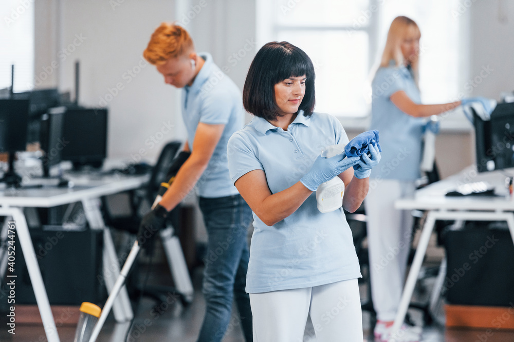 Cleans floor. Group of workers clean modern office together at daytime Cleans floor. Group of workers clean modern office together at daytime