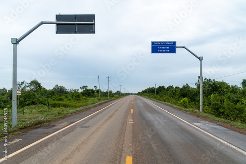 Porto Velho, RO / Brazil December 15, 2020 : View of BR 319 road and  border of Rondonia and Amazonas state sign, Amazon rainforest, Brazil. Concept of logistics, co2, global warming and transport.