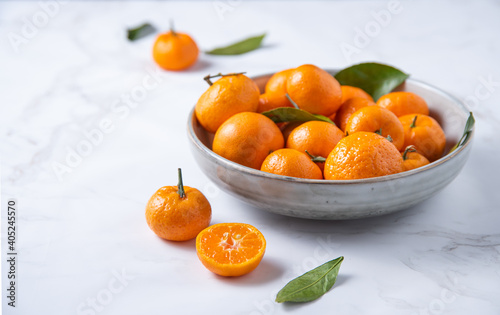 Sweet tangerines in a ceramic bowl on a white marble background © Kufotos