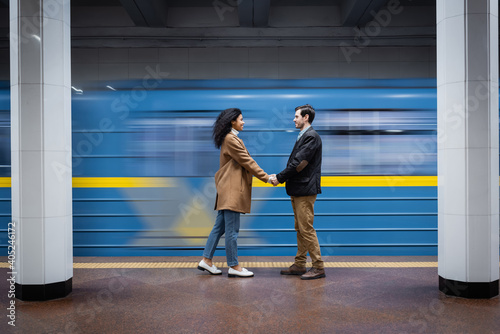 long exposure of interactional couple holding hands while standing near wagon in subway