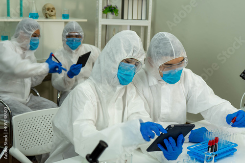 Group of four Asian medical scientists wearing PPE protective suits working with blood sample in laboratory.  Healthcare and medicine concept. virus pandemic concept. 