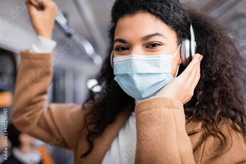 young african american woman in medical mask listening music in subway