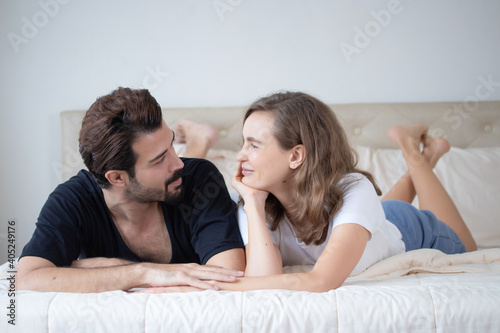 Portrait of young happy couple lying together in bed at morning. Romantic couple in love concept.