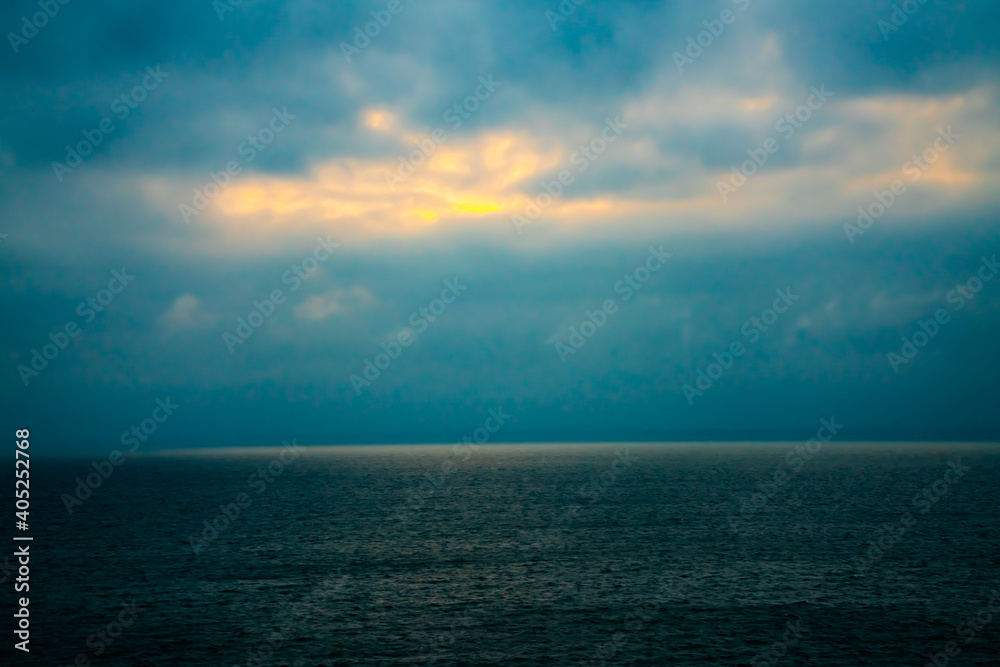 Sunlight breaking through dark gloomy clouds at sea.
