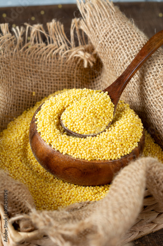 Millet. Millet in a wooden spoon and bowl on a wooden kitchen table