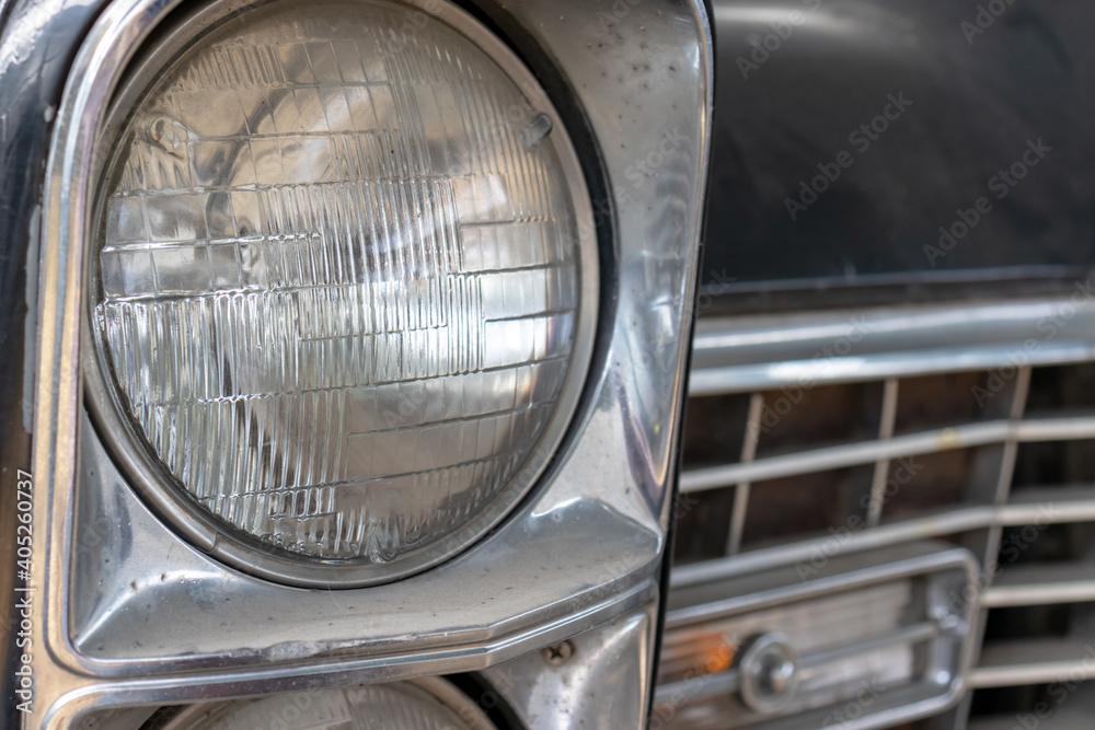 A headlight of a retro old car close up in a junk yard, recycling fee concept