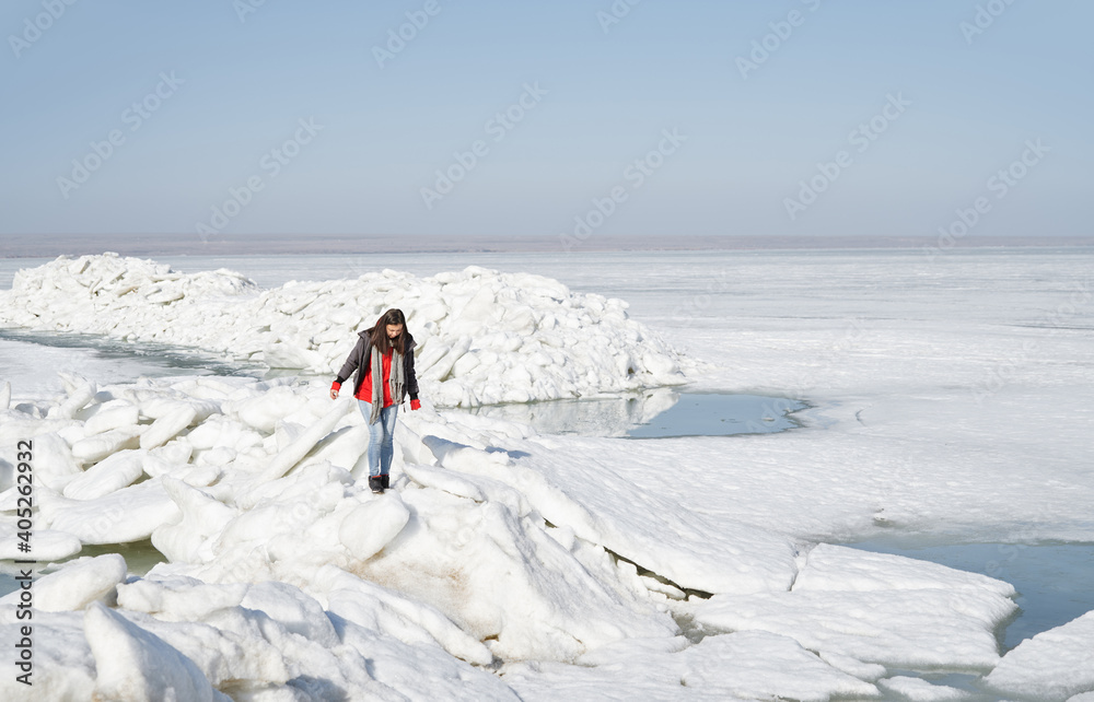 Young adult woman outdoors travelling with backpack in icy landscape