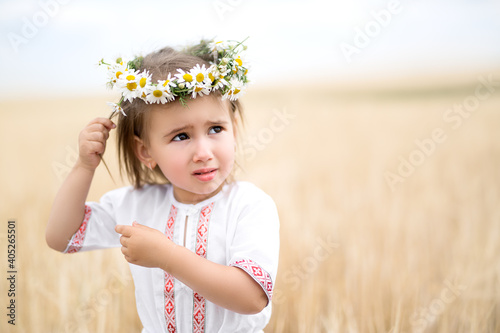 girl in a wheat field. beautiful wreath in the hair of a little girl. A child walks in a national costume