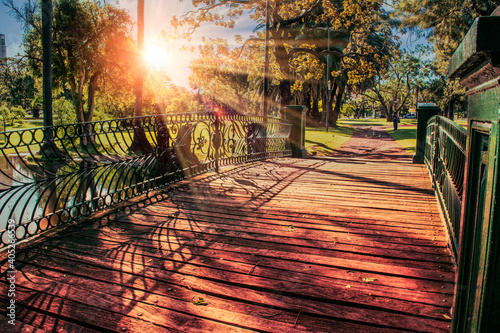 old wooden and iron bridge in city park in autumn