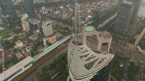 Aerial pedestal tilting into overhead view of the top of the Wisma 46 skyscraper in Jakarta, Indonesia on a cloudy day photo