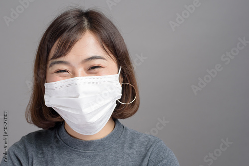 Portrait of young beautiful asian woman wearing a surgical mask over studio background, covid19 pandemic and air pollution (pm2.5).