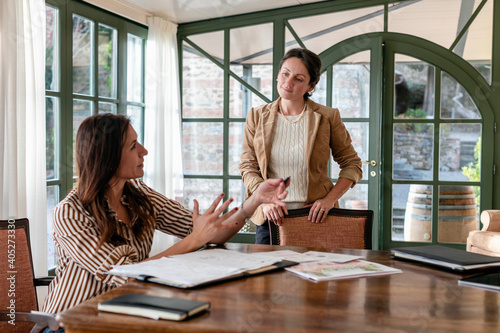 Creative female event planner discussing with colleague in meeting at home photo