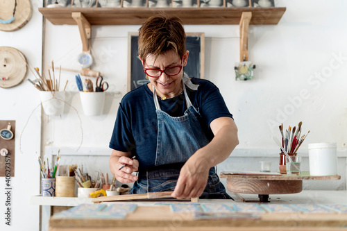 Mature female craftsperson working in ceramics store photo