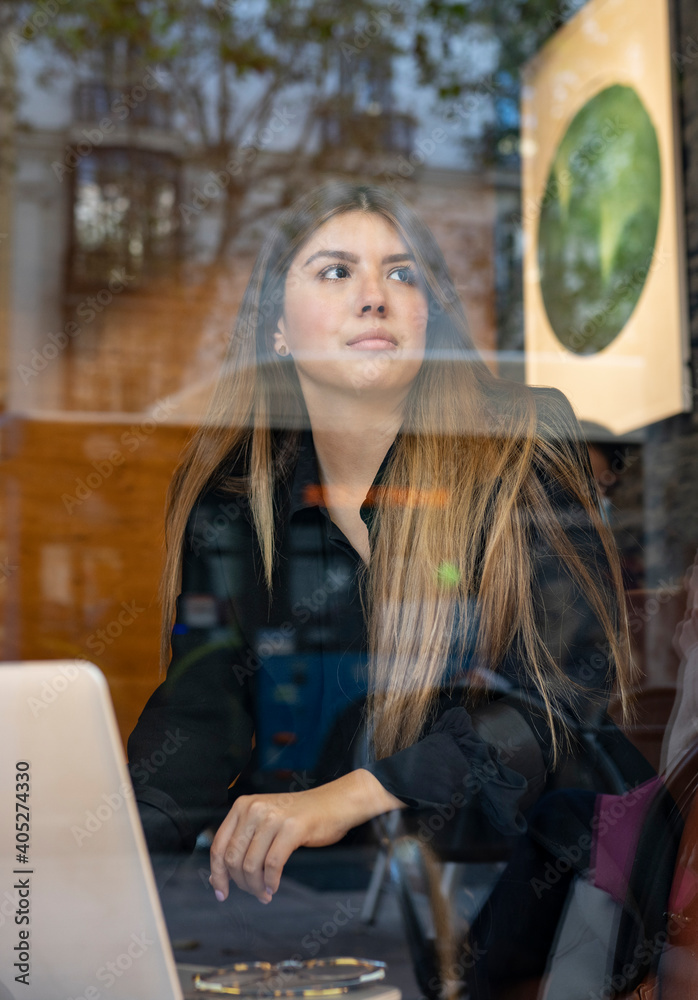 Woman with laptop looking away while sitting at cafe Woman with laptop looking away while sitting at cafe