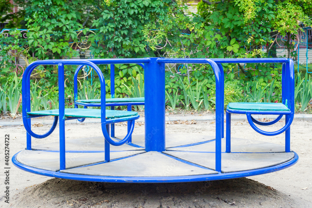 Empty сhildren's metal carousel on outdoor playground. Concept of entertaining street leisure for children, improvement of the urban environment. An empty Playground during the pandemic Empty сhildren's metal carousel on outdoor playground. Concept of entertaining street leisure for children, improvement of the urban environment. An empty Playground during the pandemic