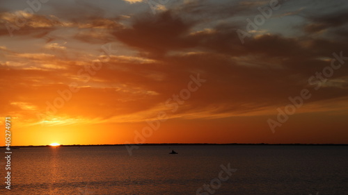 Sun and clouds reflected in on Launa Madre during dazzling sunset while kayak glides by; Texas gulf coast 