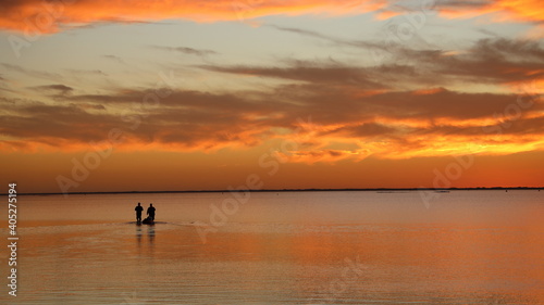 Two people wade in calm water during sensational, colorful sunset at Padre Island, Texas © Michelle