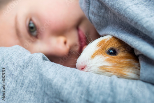 Boy holding a guinea pig. A child hugs a guinea pig. Pet care concept