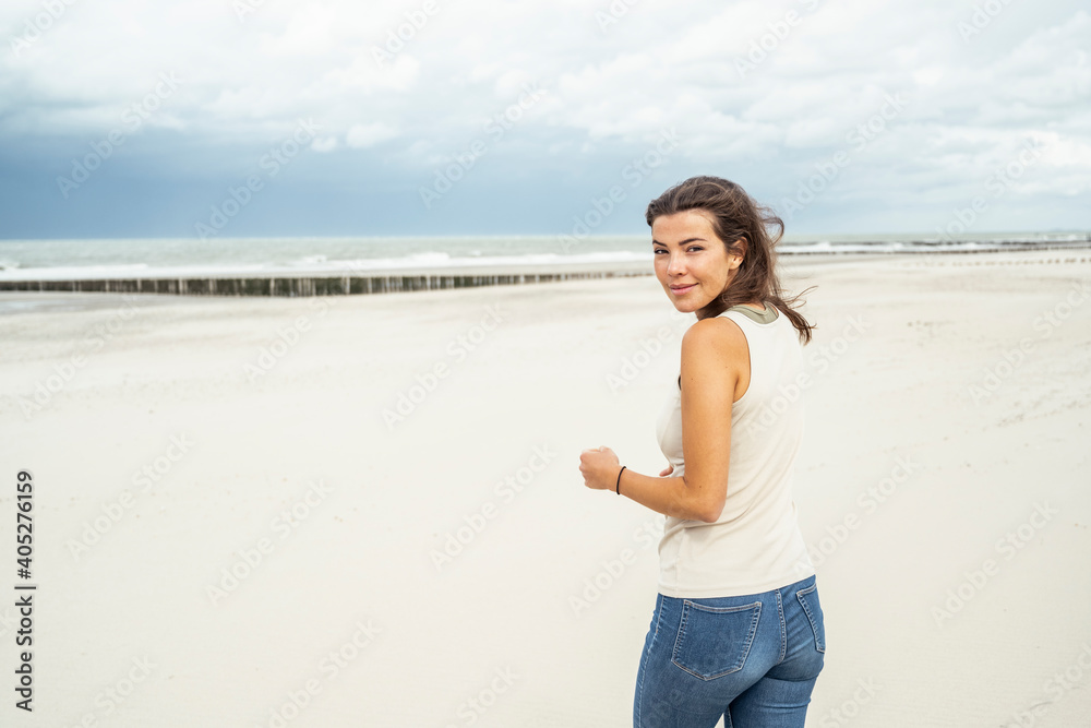 Young woman smiling while walking against sky Young woman smiling while walking against sky