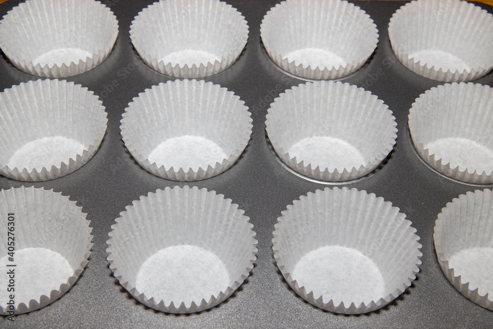 A metal baking tray fill of cup cake holders ready to be put in some cake mix A metal baking tray fill of cup cake holders ready to be put in some cake mix