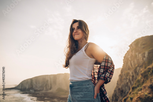 Smiling woman looking at view while standing with hand in pocket against sky photo