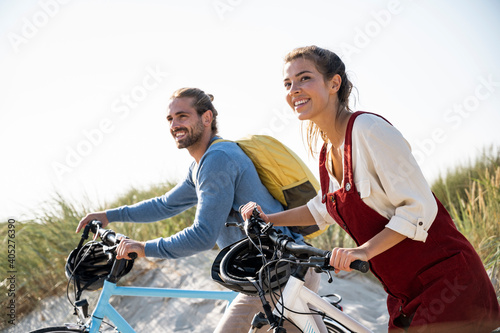 Couple with bicycles walking against clear sky