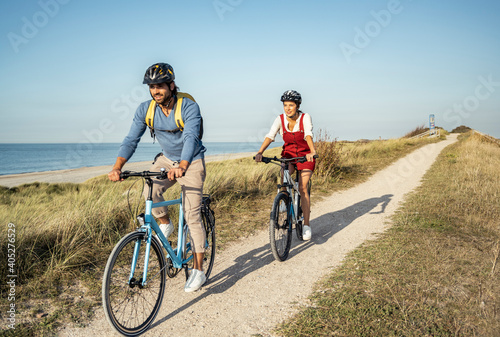 Girlfriend and boyfriend riding bicycles on sunny day against clear sky