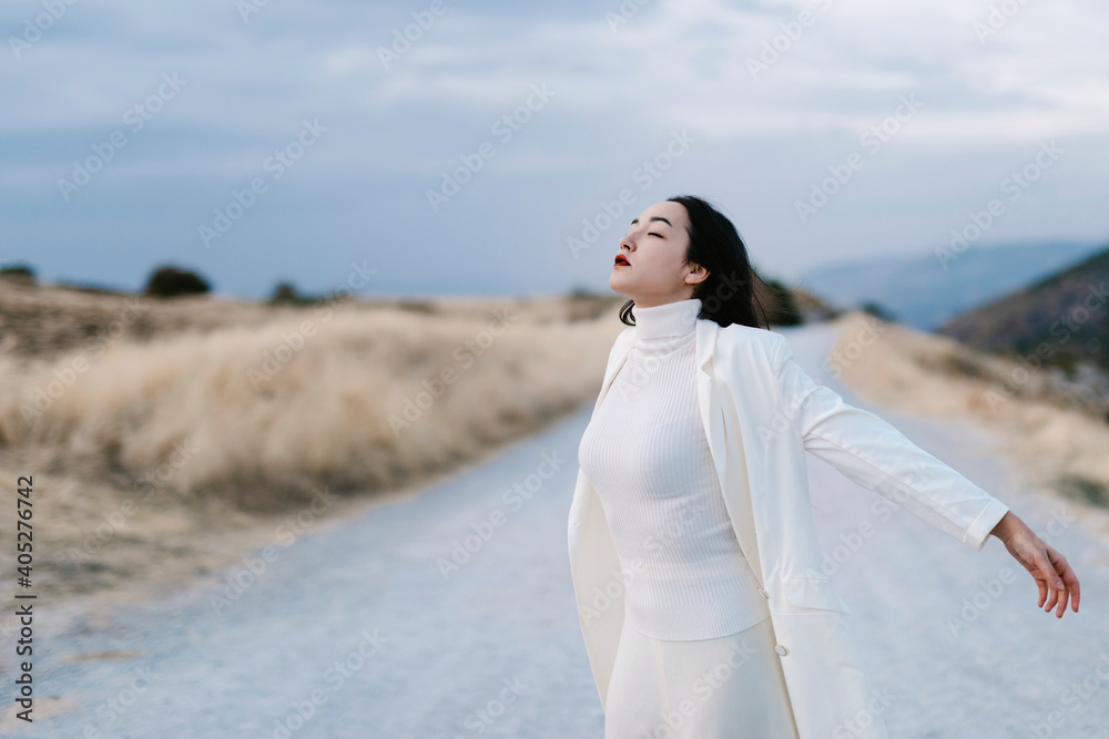 Woman with eyes closed and arms outstretched standing on road Woman with eyes closed and arms outstretched standing on road