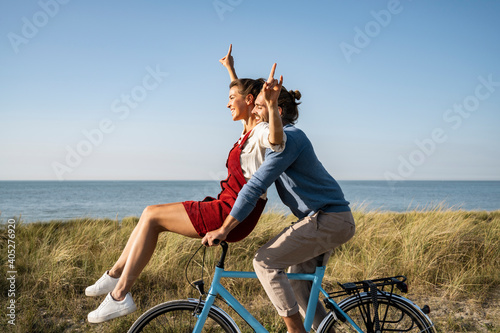 Happy couple enjoying bicycle ride together against clear sky photo