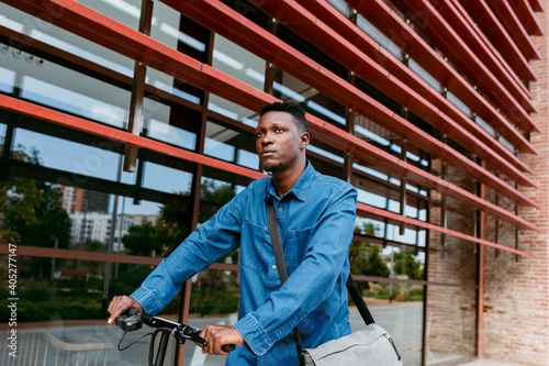 Thoughtful male commuter walking with electric push scooter in city